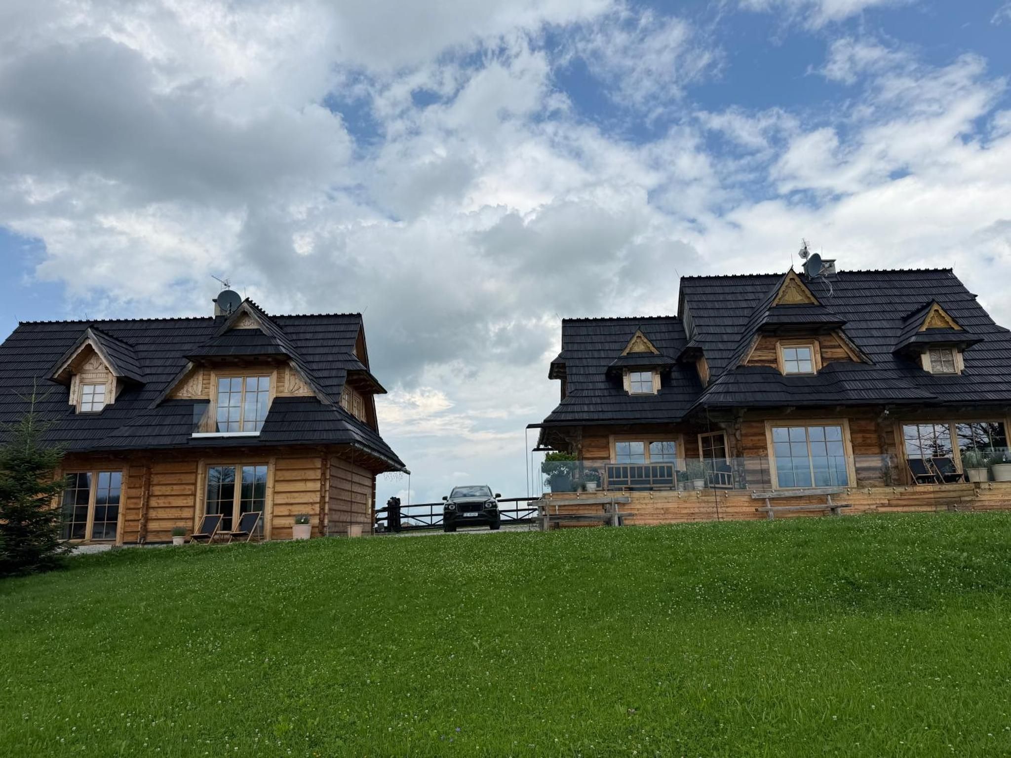 Dwa drewniane chalety na zielonej łące pod błękitnym niebem